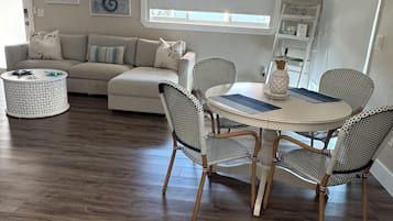Ein Essbereich mit einem runden Tisch, vier Stühlen, einer weißen Vase und einem Deckenventilator.