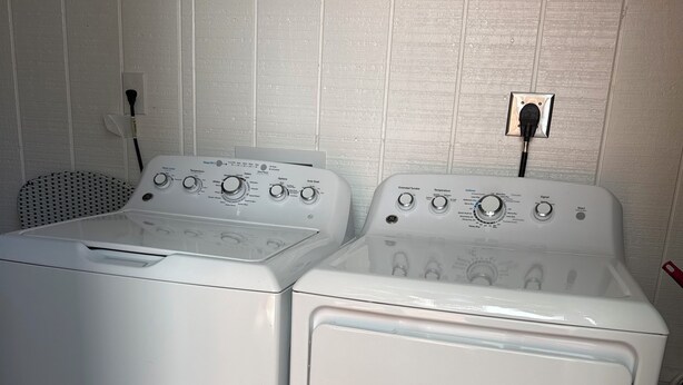 Twee voorladers wasmachines in een wasserij met een betegelde vloer en een ventilatieopening in de muur.