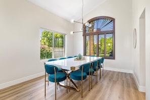 Uma sala de jantar com uma mesa grande, cadeiras azuis e um lustre moderno.