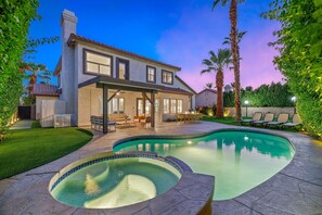 Une maison à deux étages avec une piscine, du mobilier de jardin et une pelouse bien entretenue.