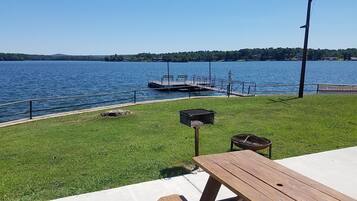 A lakeside view with a dock, grassy area, and picnic table.