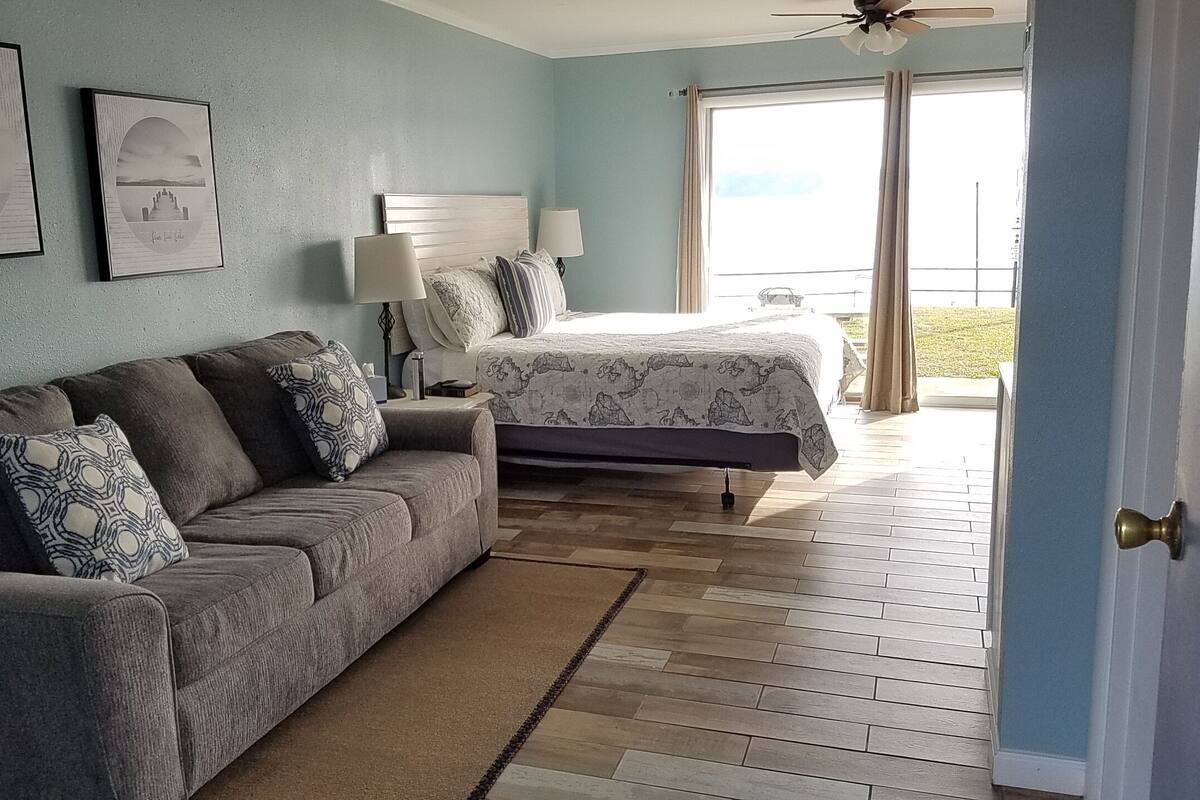 A bedroom with a bed, a sofa, and a window.