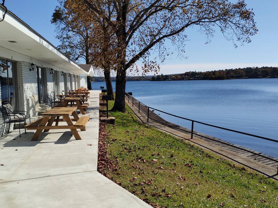 Un bâtiment situé au bord du lac, doté de tables de pique-nique et d’un espace extérieur aménagé pour s’asseoir.