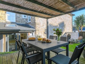 An outdoor patio with a table set for breakfast, including croissants and orange juice.