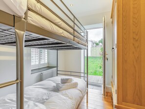 A bunk bed room with a view of a grassy yard.