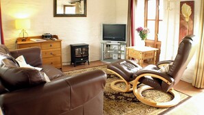 A living room with a sofa, a recliner, a TV, a small table with a vase, and a mirror on the wall. - The Mealhouse-UK12902 (Pelynt, near Looe)