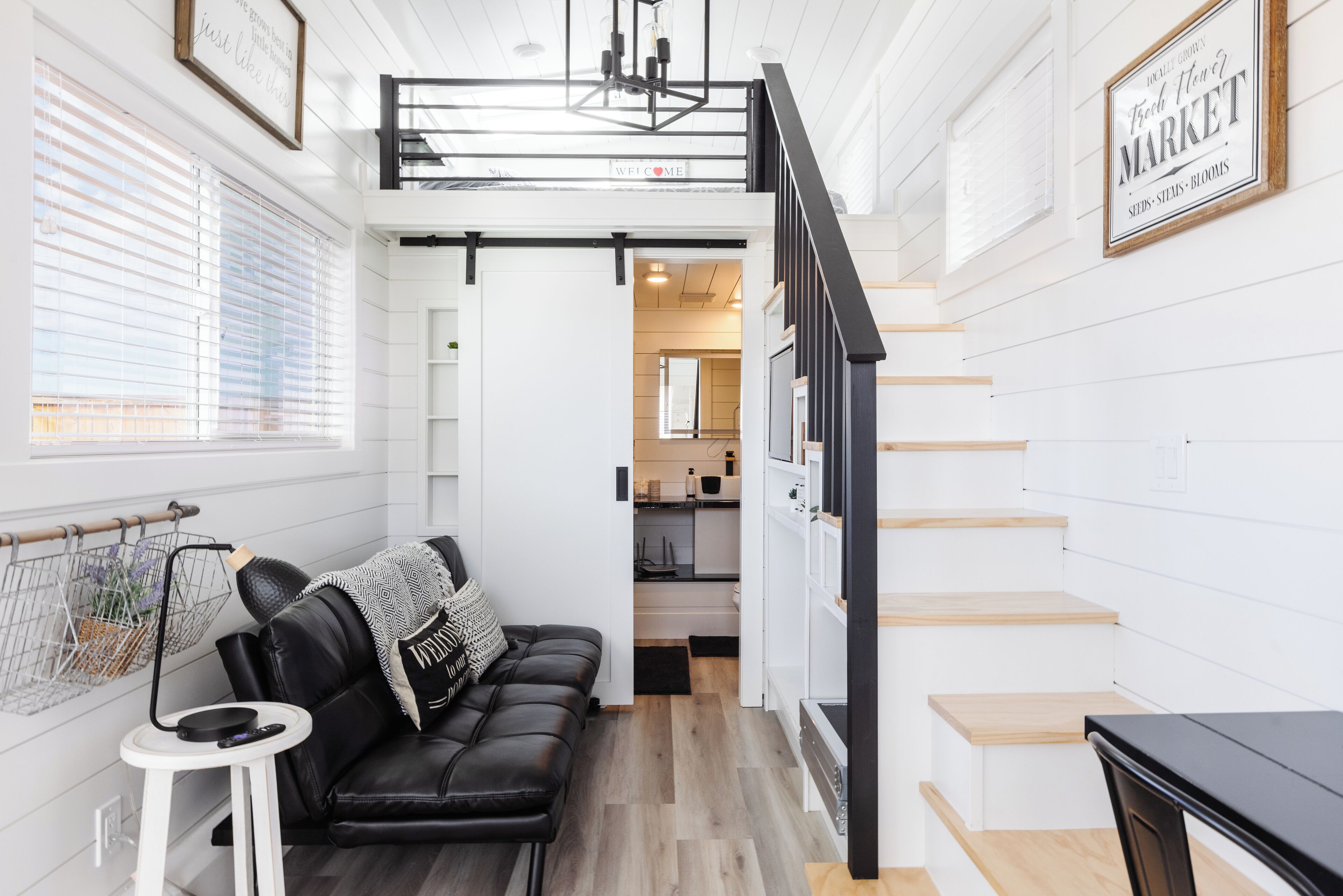 A modern interior with a black leather sofa, a small white table, and a staircase leading to an upper level.