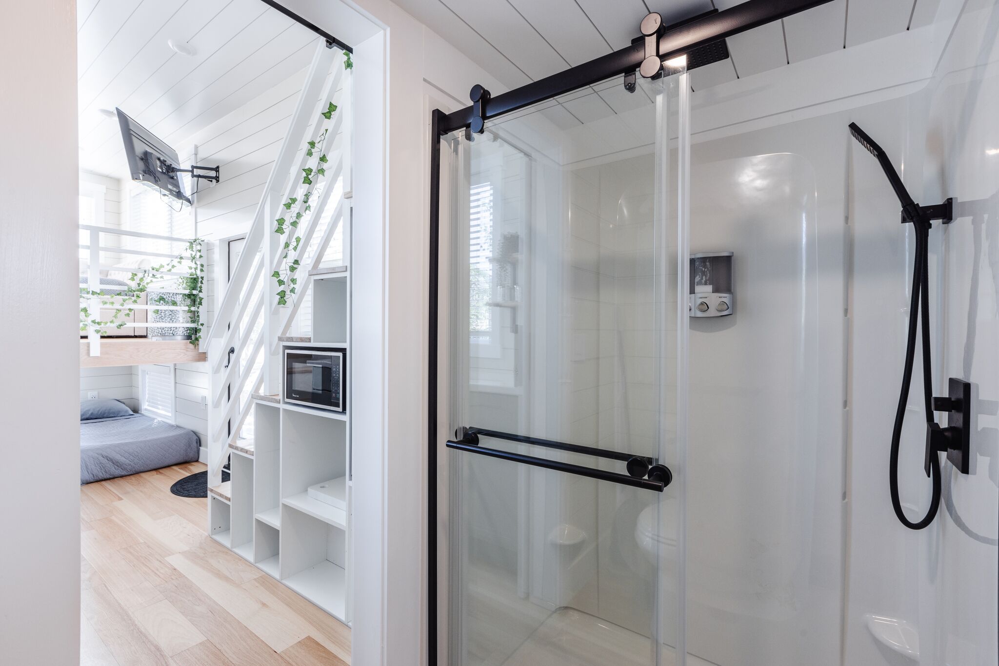 Ein modernes Badezimmer mit Duschkabine aus Glas, einem schwarzen Handtuchhalter und einer weißen Toilette.