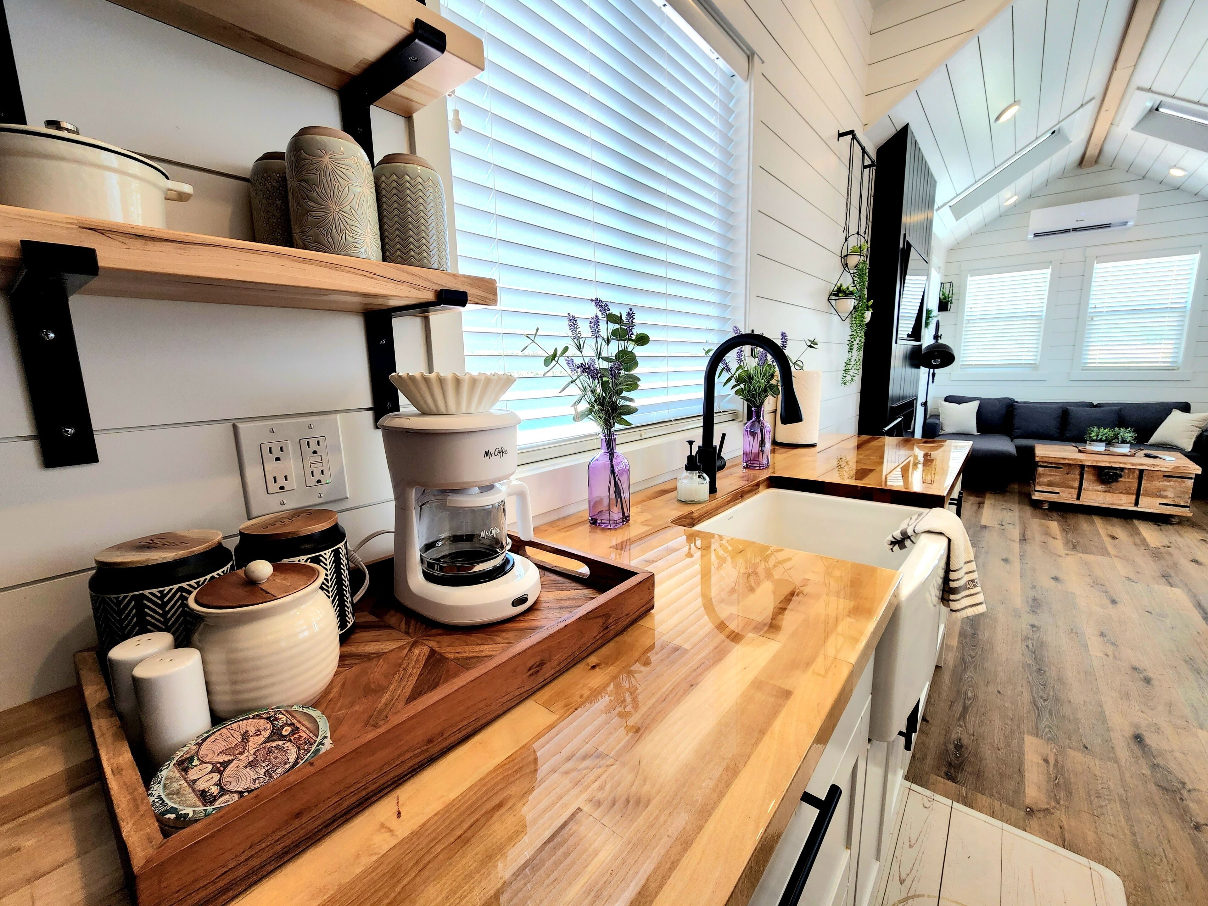 Una cocina moderna con mostradores de madera, una cafetera y frascos decorativos.