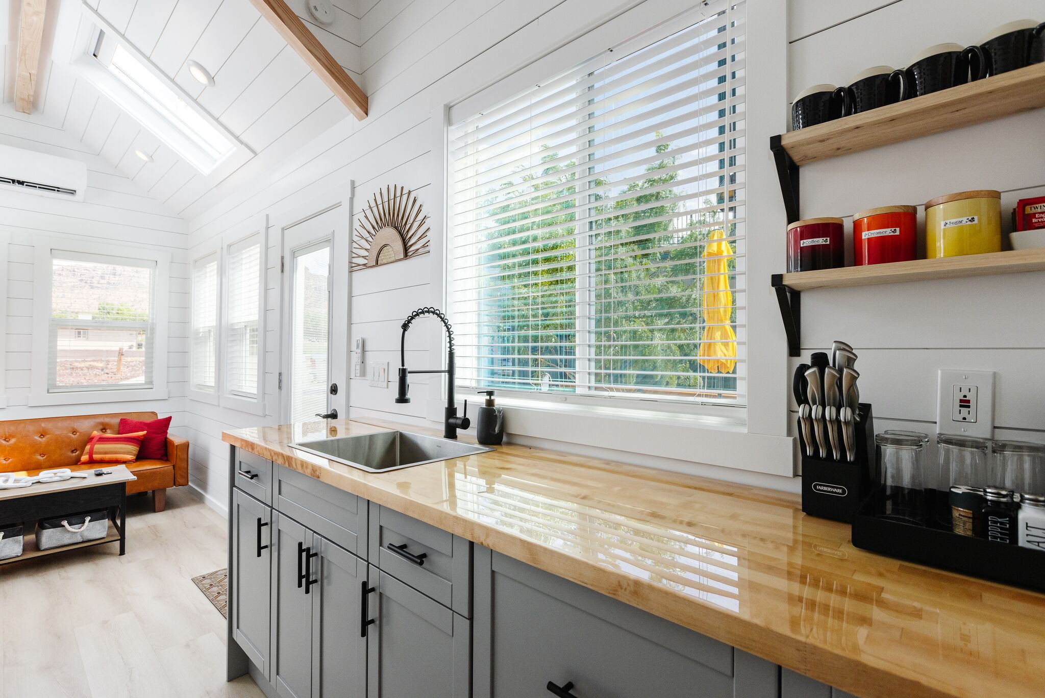 A kitchen with a wooden countertop, a sink, and a window with blinds.