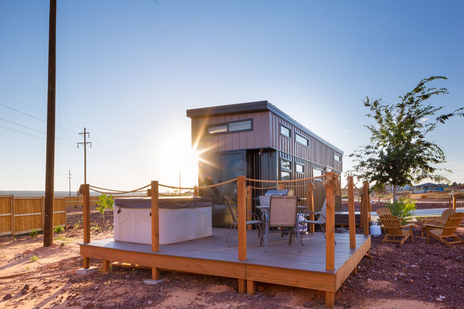A modern building with a deck, outdoor seating, and a view of the sunset.