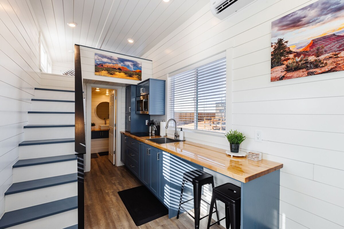 A modern kitchen with a wooden countertop, blue cabinets, and a black bar stool.