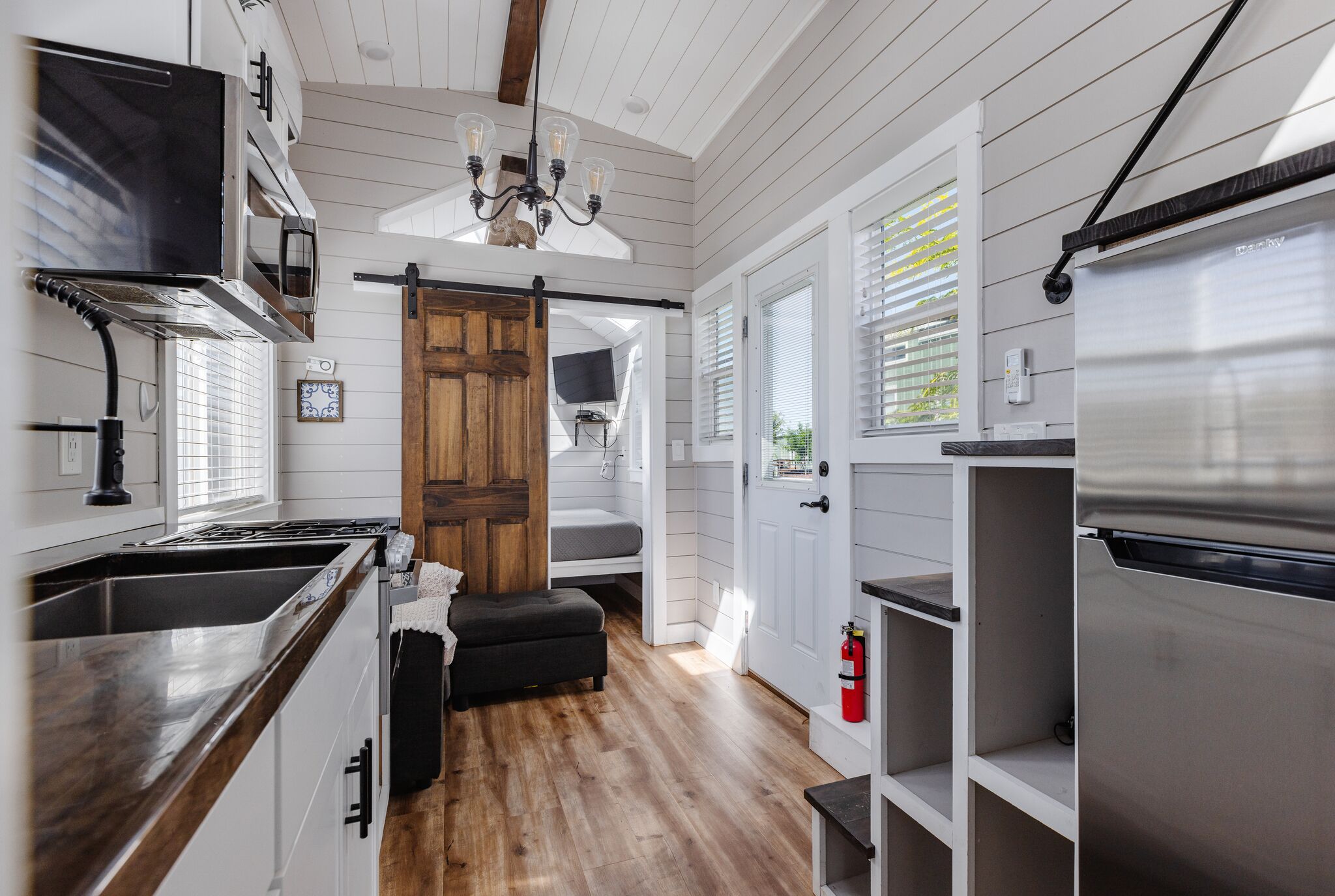 A kitchen with a wooden bench, a stainless steel refrigerator, and a wooden door.