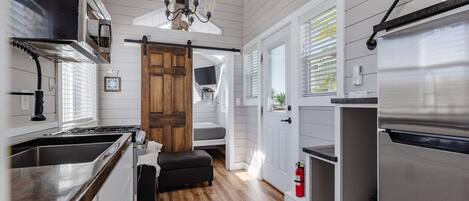 A kitchen with a wooden bench, a stainless steel refrigerator, and a wooden door.