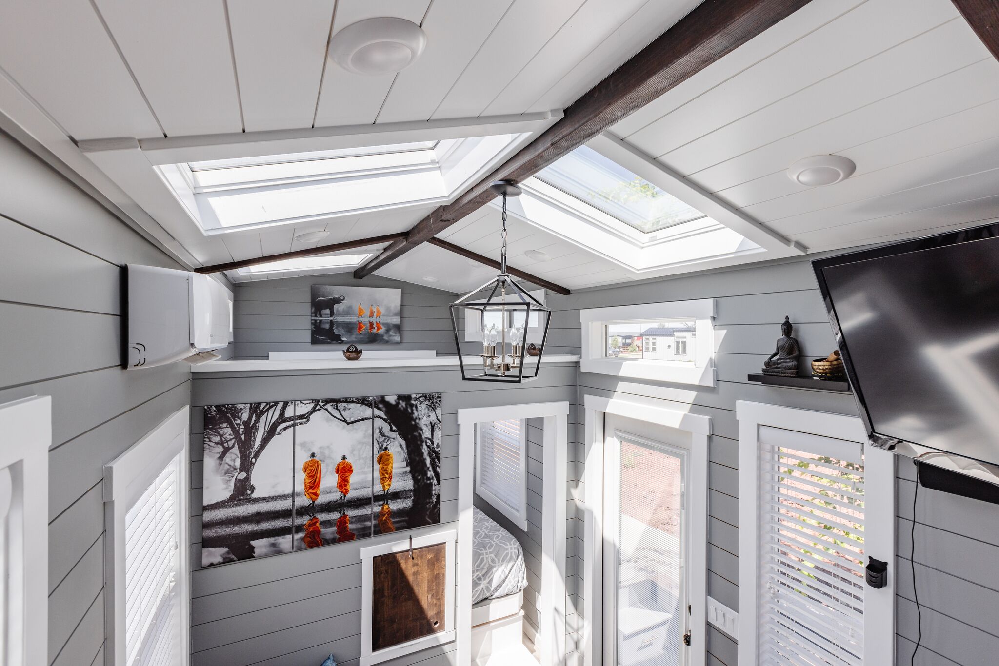 A room with skylights, a bed, a TV, and artwork on the walls.