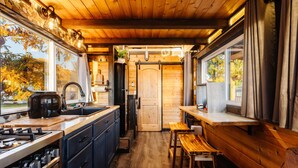 A compact kitchen with wooden cabinets, a stove, and a sink. - Zion's Tiny Getaway (Hurricane)