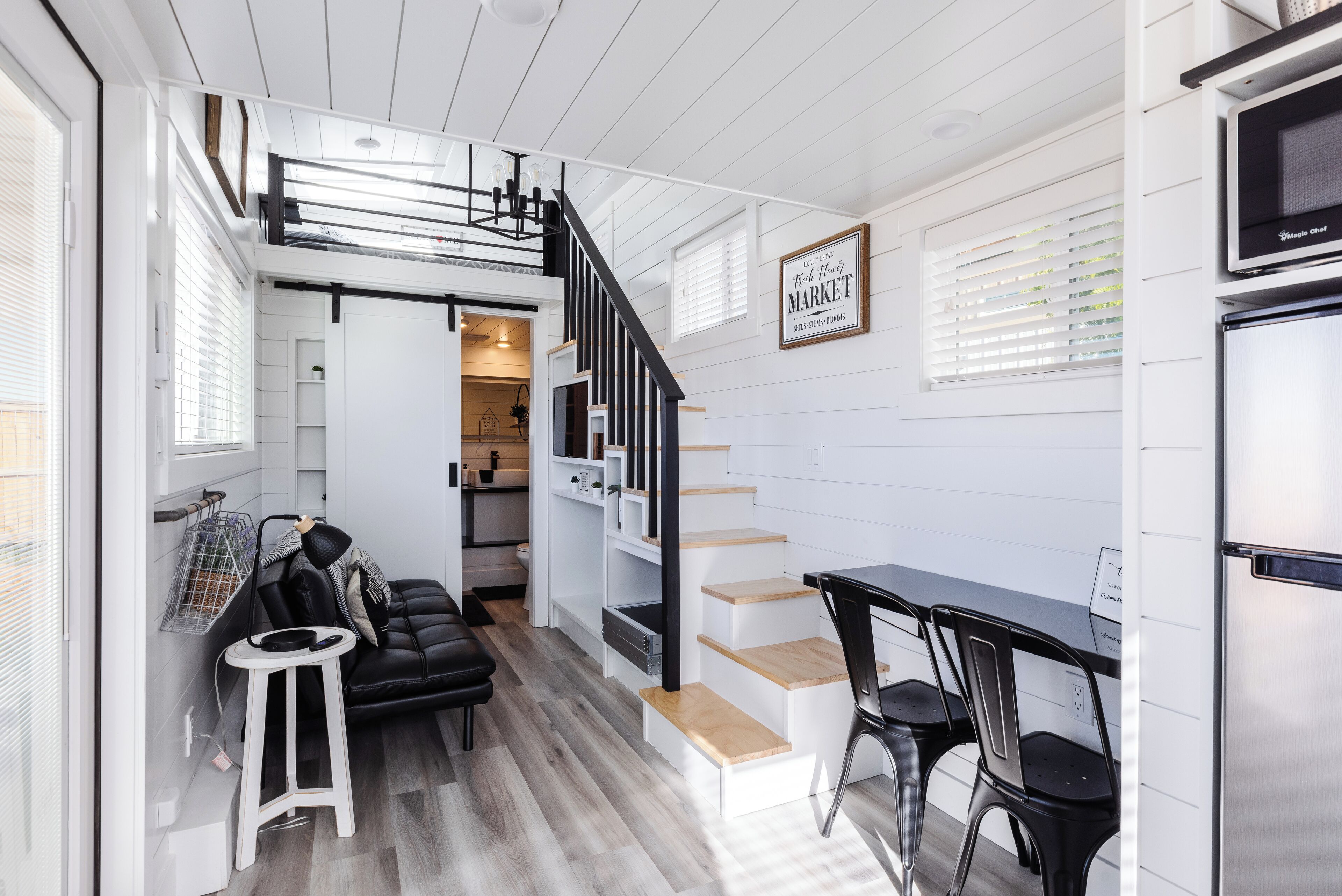 A compact kitchen with a black countertop, white cabinets, and a stainless steel refrigerator.