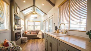 A modern kitchen with a built-in oven, a sink, and a window with blinds. - Zion's Tiny Getaway (Hurricane)