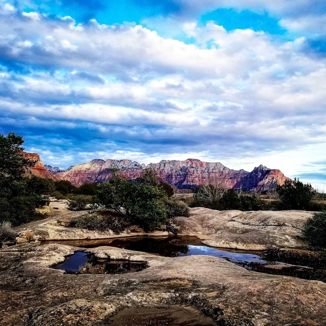 Un paisaje natural con montañas, un pequeño arroyo y vegetación escasa.