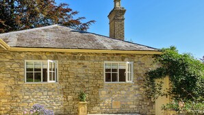 A stone house with two windows, a chimney, and a garden with a wooden planter. - La Rose - Gillingham, Shaftesbury (West Stour)