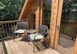 Relax on the elevated deck with seating for two, surrounded by lush vegetation.