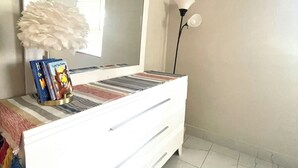 Une commode blanche avec un miroir, une lampe décorative et quelques livres.