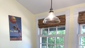 A dining area with a glass table, wicker chairs, and a hanging light fixture. - Old Town Classic with plenty of charm, porch swing and parking (Key West)