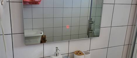 A bathroom with a white sink, a mirror, and a towel rack with yellow and pink towels.