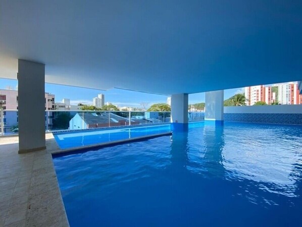 Une piscine intérieure à l’eau d’un bleu limpide, entourée d’un sol carrelé et soutenue par des colonnes.