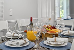 A dining table set with plates, glasses, a pitcher of orange juice, and a fruit platter.