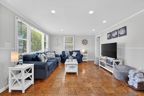 A living room with a blue sofa set, a coffee table, a TV stand, and a fireplace.