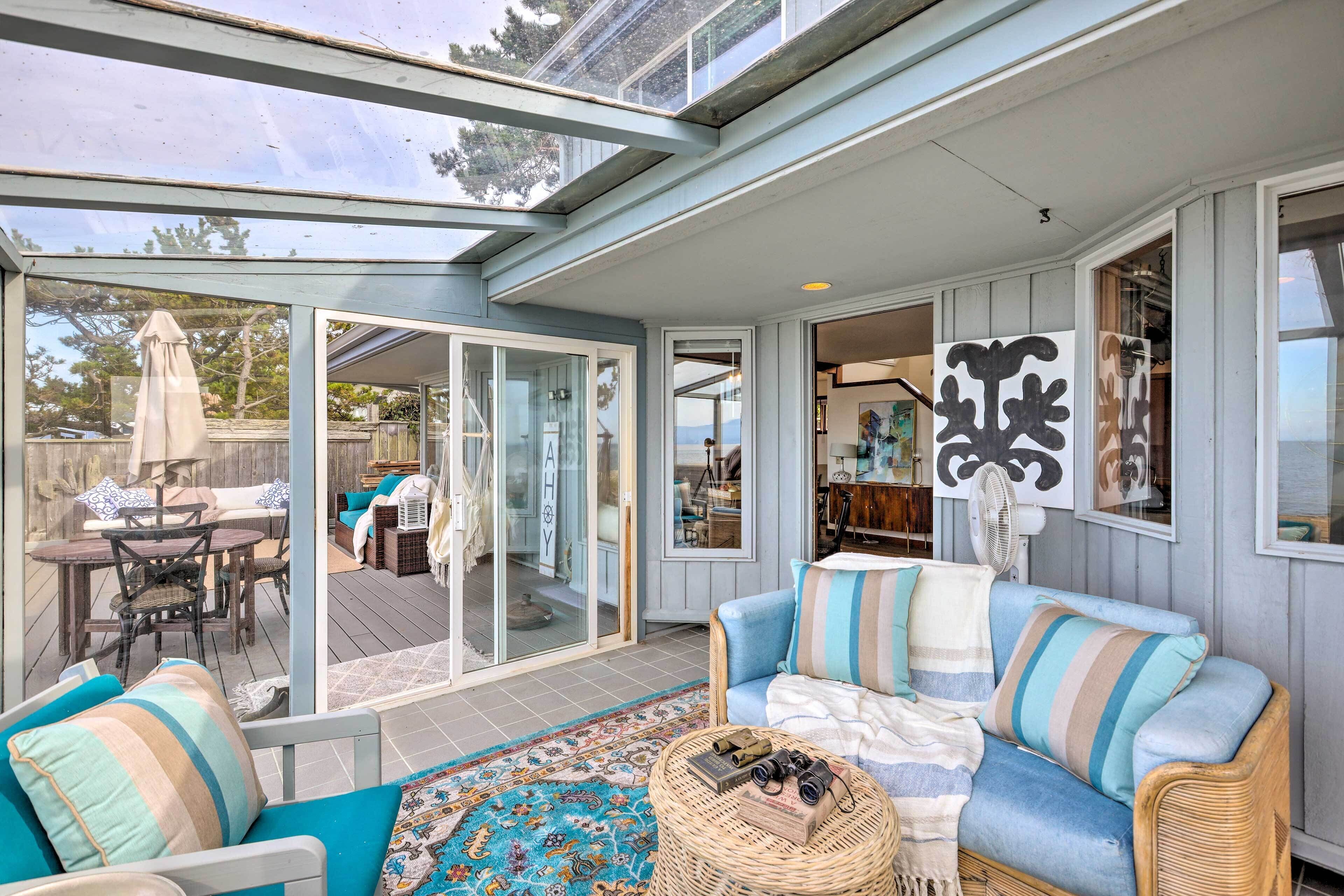 A cozy living area with a sofa, a wicker side table, and a glass door leading to a deck.