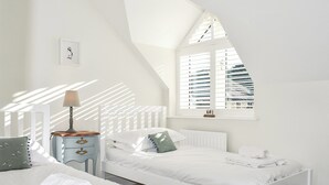 A bedroom with two beds, a window with blinds, a bedside table with a lamp, and a framed picture on the wall. - 2 bedroom accommodation in Beadnell, nr Chathill (Beadnell, nr Chathill)
