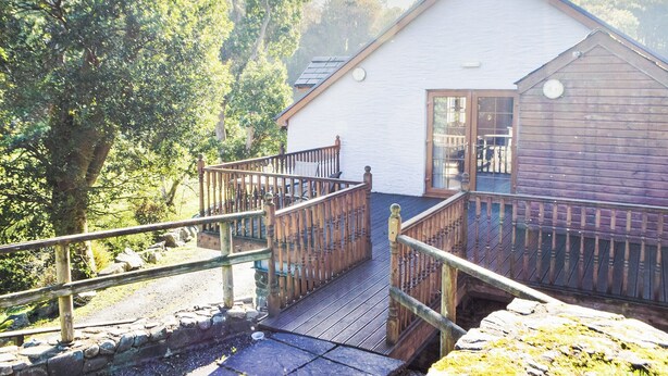 A white building with a wooden deck and a stone wall. - 1 bedroom accommodation in Capel Dewi (Capel Dewi)