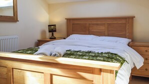 A bedroom with a wooden bed, a nightstand with a lamp, a skylight, and a radiator. - 1 bedroom accommodation in Capel Dewi (Capel Dewi)