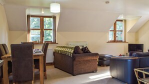 A cozy living room with a dining table, two sofas, and a TV. - 1 bedroom accommodation in Capel Dewi (Capel Dewi)