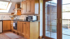 A kitchen with wooden cabinets, a microwave, and a toaster. - 1 bedroom accommodation in Capel Dewi (Capel Dewi)