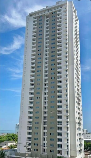 Un grand immeuble moderne, avec de nombreux balcons, et un ciel dégagé en arrière-plan.