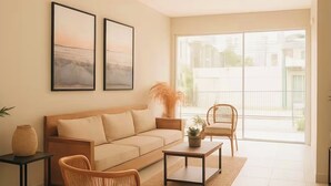 A modern living room with a sofa, a coffee table, and two wicker chairs. There are two framed pictures on the wall, a vase on a side table, and a large window with a view of buildings. - Luxury apartment with ocean view only 5 min from the historic center. (Cartagena de Indias)