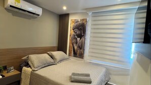 A modern bedroom with a bed, bedside table, air conditioning unit, and a large Buddha statue. - Luxury apartment with ocean view only 5 min from the historic center. (Cartagena de Indias)