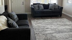 A living room with a dark-colored sofa, a patterned rug, and a white door. - Cozy Stay Near National Parks & BYUI - Sleeps 6 (Rexburg)