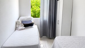 A bedroom with a bed, a wardrobe, a window with curtains, and a teddy bear. - Casa Família: Praia, Campeche e Conforto (Florianópolis)
