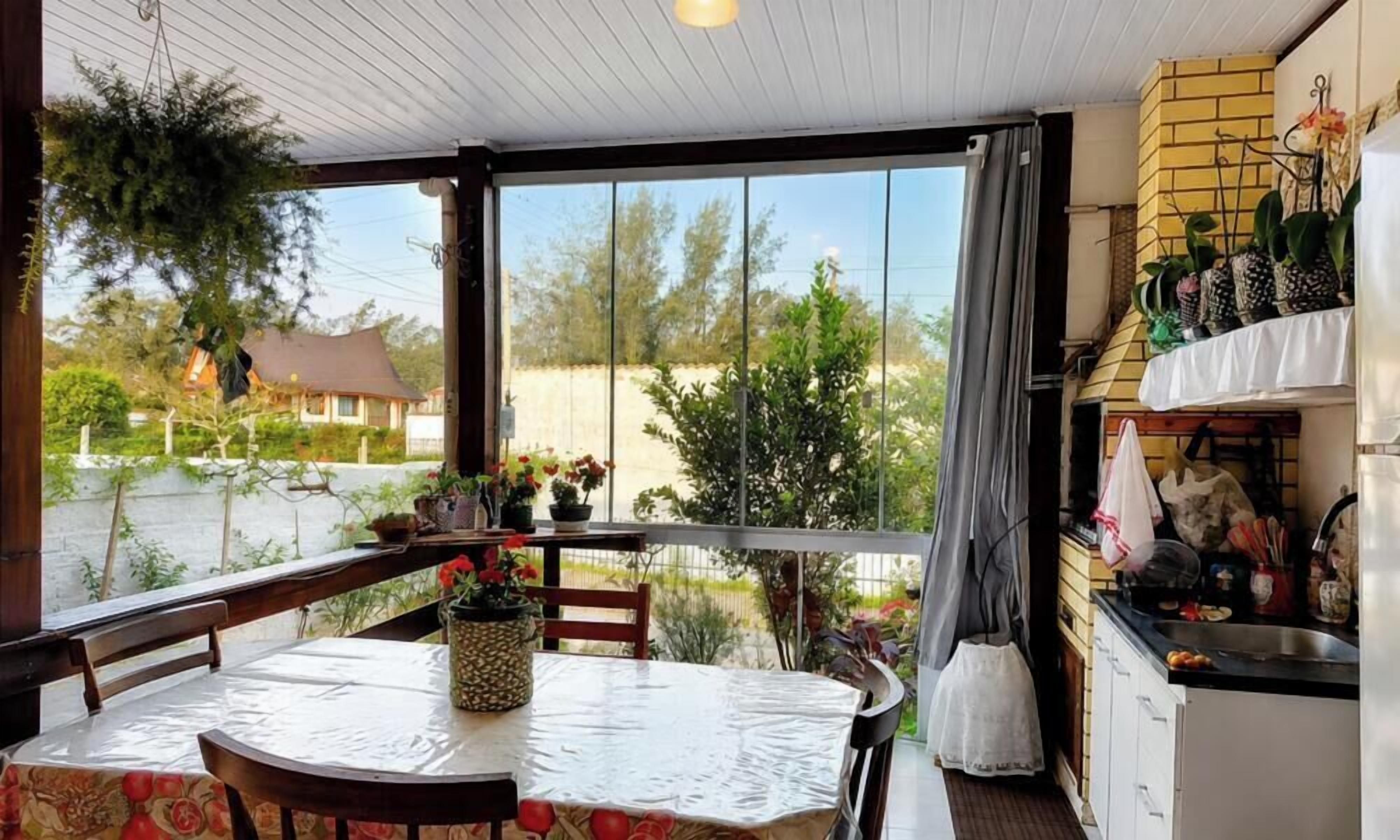 A covered patio with a table and chairs, a kitchen area with a sink and cabinets, and a view of the surrounding landscape.