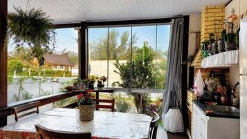 A covered patio with a table and chairs, a kitchen area with a sink and cabinets, and a view of the surrounding landscape.