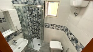 A bathroom with a glass shower enclosure, a sink, and a toilet. - Sea and sun appartment whole accommodation (napoli)