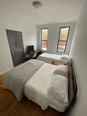 A room with two beds, a desk, and a computer.