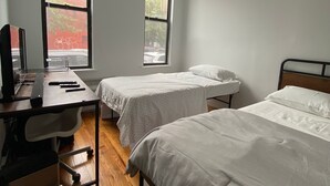 A room with two single beds, a desk with a computer, and a chair. There are two windows providing natural light. - room in brooklyn (Brooklyn)
