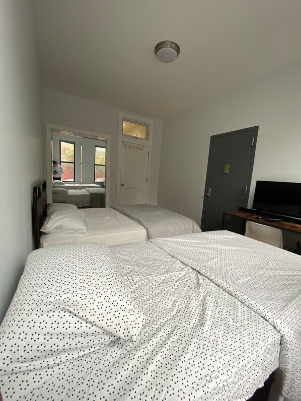A room with two beds, a door, a television, and a window.