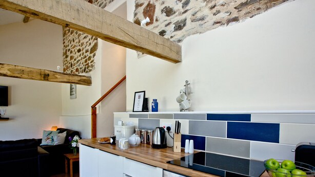 A modern kitchen with a wooden countertop, built-in oven, and a stone wall.