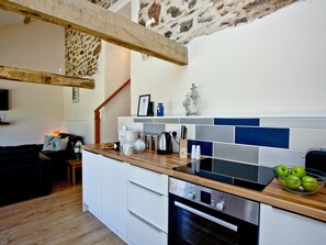 Une cuisine moderne avec un plan de travail en bois, un four encastré et un mur en pierre.